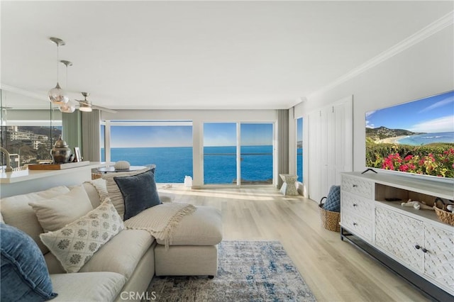 living room with ornamental molding, a water view, wood finished floors, and ceiling fan