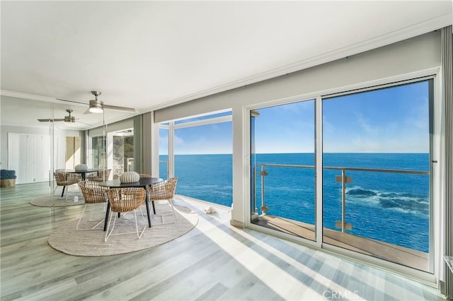 sunroom / solarium featuring crown molding, a water view, and wood finished floors