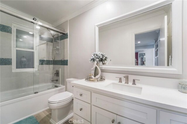 bathroom with crown molding, wood finished floors, vanity, toilet, and shower / bath combination with glass door