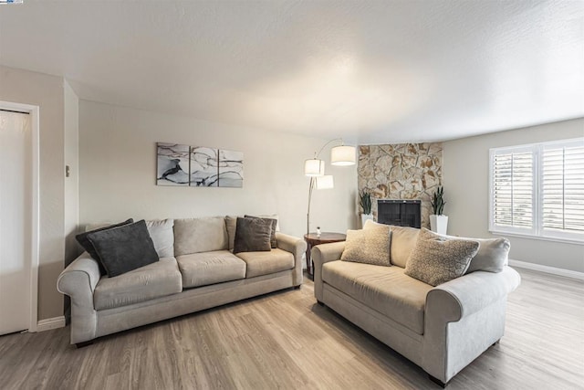 living room featuring light hardwood / wood-style floors and a stone fireplace