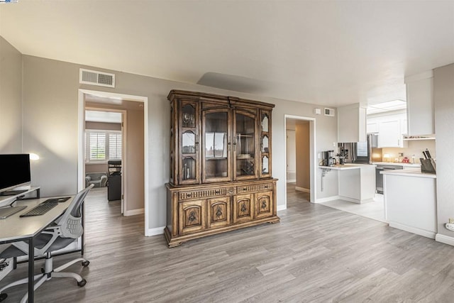 kitchen featuring kitchen peninsula, dishwasher, white cabinets, and light wood-type flooring