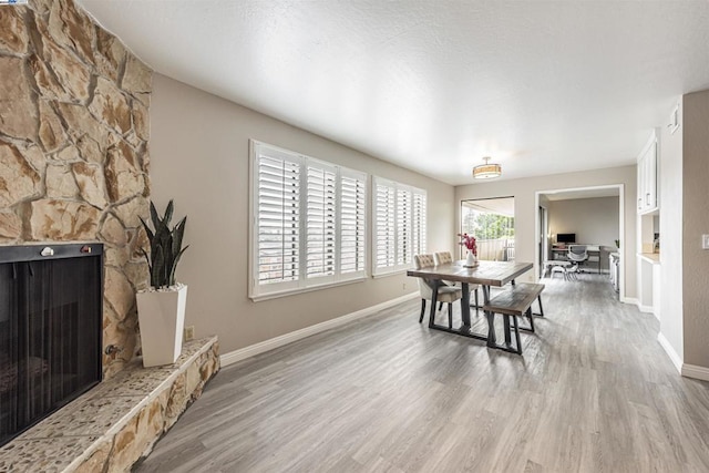 dining area with light hardwood / wood-style flooring and a stone fireplace