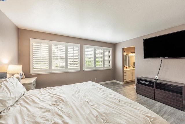 bedroom with light hardwood / wood-style flooring and ensuite bath