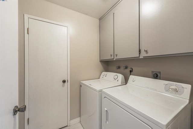 clothes washing area with cabinets and washing machine and clothes dryer