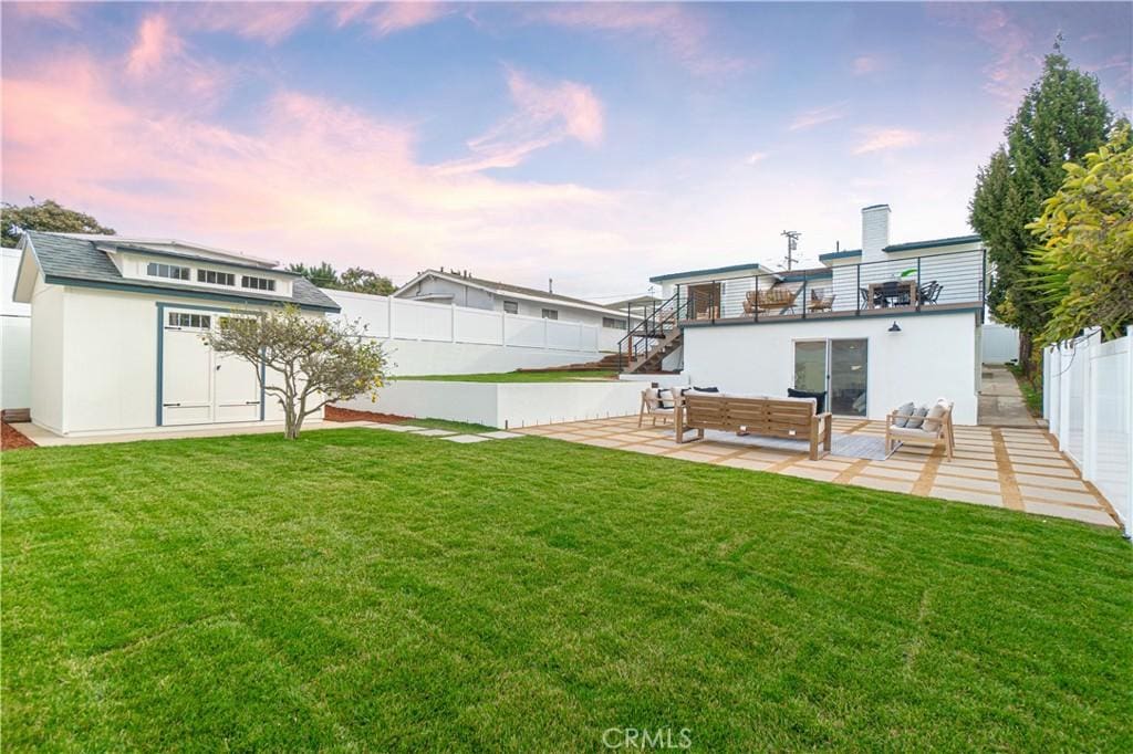 yard at dusk with an outdoor hangout area, a balcony, and a patio area