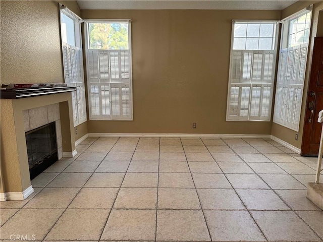 unfurnished living room featuring light tile patterned floors, a healthy amount of sunlight, and a tiled fireplace