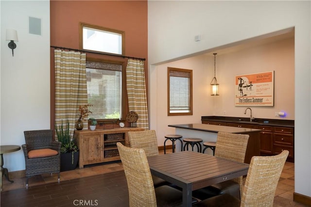 dining area featuring a high ceiling, a wealth of natural light, dark wood-type flooring, and sink