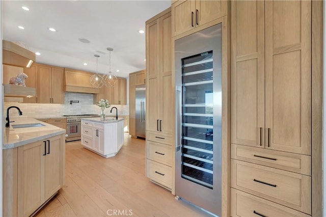 kitchen featuring sink, beverage cooler, premium appliances, premium range hood, and light brown cabinetry