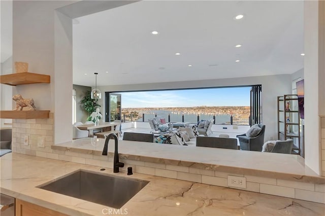 kitchen featuring backsplash, light stone counters, and sink