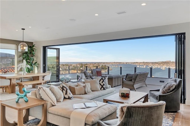 living room featuring a healthy amount of sunlight, a water view, and light hardwood / wood-style floors