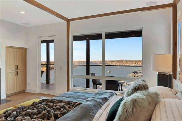 bedroom with access to exterior, light hardwood / wood-style flooring, and a water view