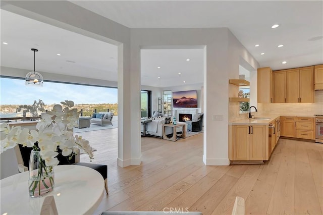 kitchen featuring hanging light fixtures, decorative backsplash, light brown cabinets, and light hardwood / wood-style floors