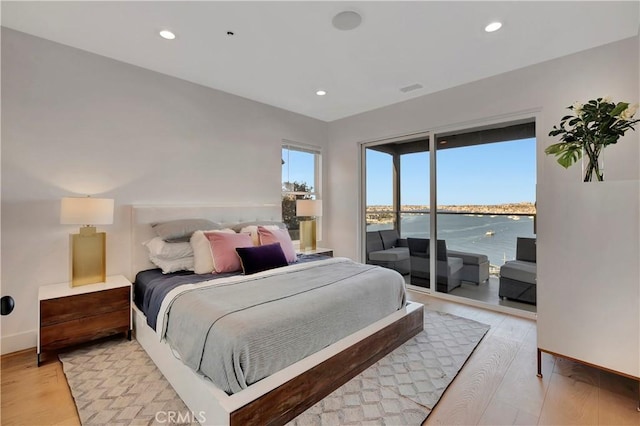 bedroom with access to outside, a water view, and light hardwood / wood-style floors