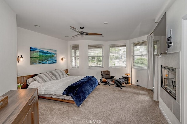 bedroom with ceiling fan, a fireplace, and light colored carpet