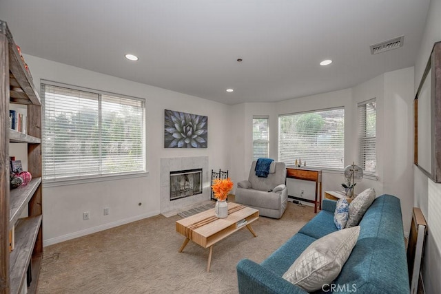 carpeted living room with plenty of natural light and a tiled fireplace