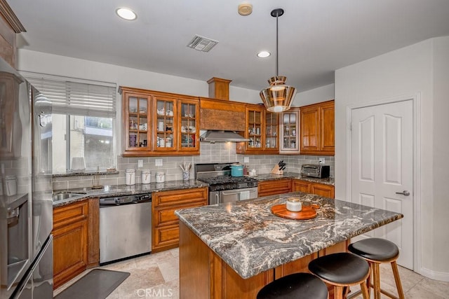 kitchen featuring a center island, hanging light fixtures, appliances with stainless steel finishes, and dark stone counters