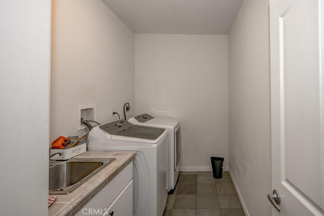 laundry area featuring separate washer and dryer, sink, light tile patterned floors, and cabinets