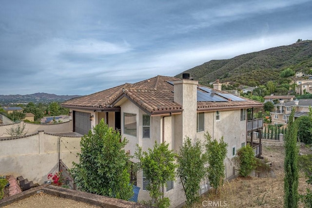 view of side of property with a mountain view, a garage, and solar panels