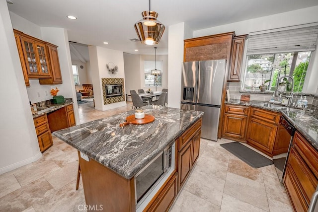 kitchen with sink, a center island, dark stone counters, and appliances with stainless steel finishes