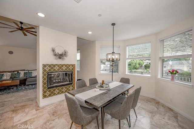 dining room with a fireplace and ceiling fan with notable chandelier