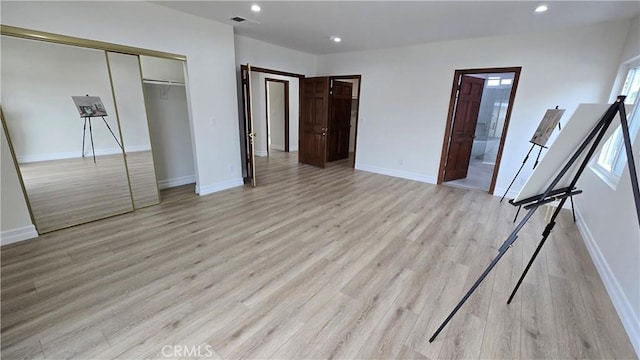 unfurnished bedroom featuring light wood-type flooring, multiple windows, and a closet