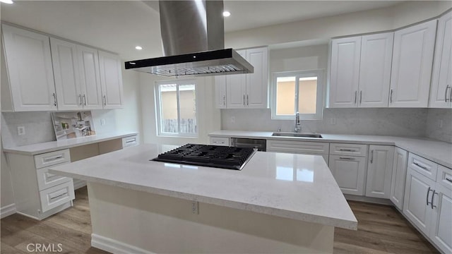 kitchen with island exhaust hood, white cabinetry, sink, and stainless steel gas cooktop