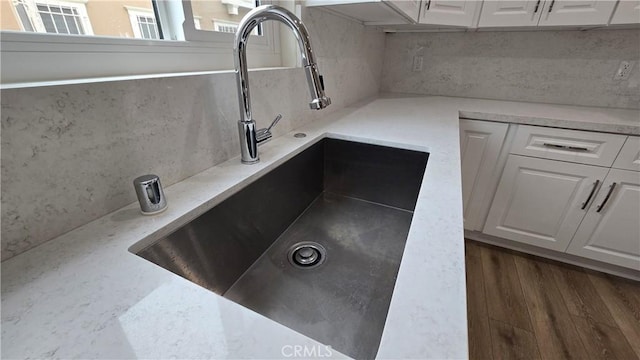 room details with white cabinetry, sink, and dark wood-type flooring