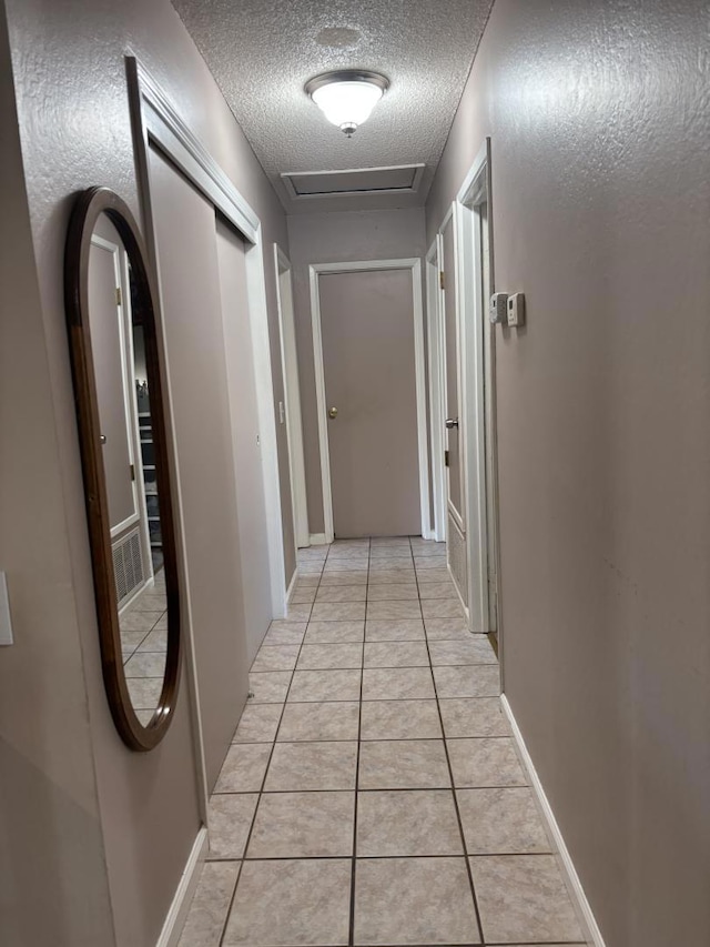 hallway featuring light tile patterned floors and a textured ceiling