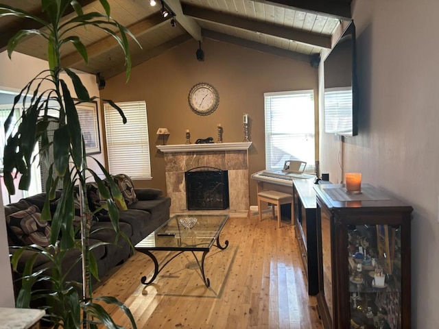 living room featuring a tile fireplace, vaulted ceiling with beams, wooden ceiling, and light wood-type flooring