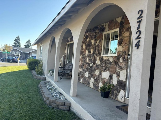 view of exterior entry with a porch and a lawn