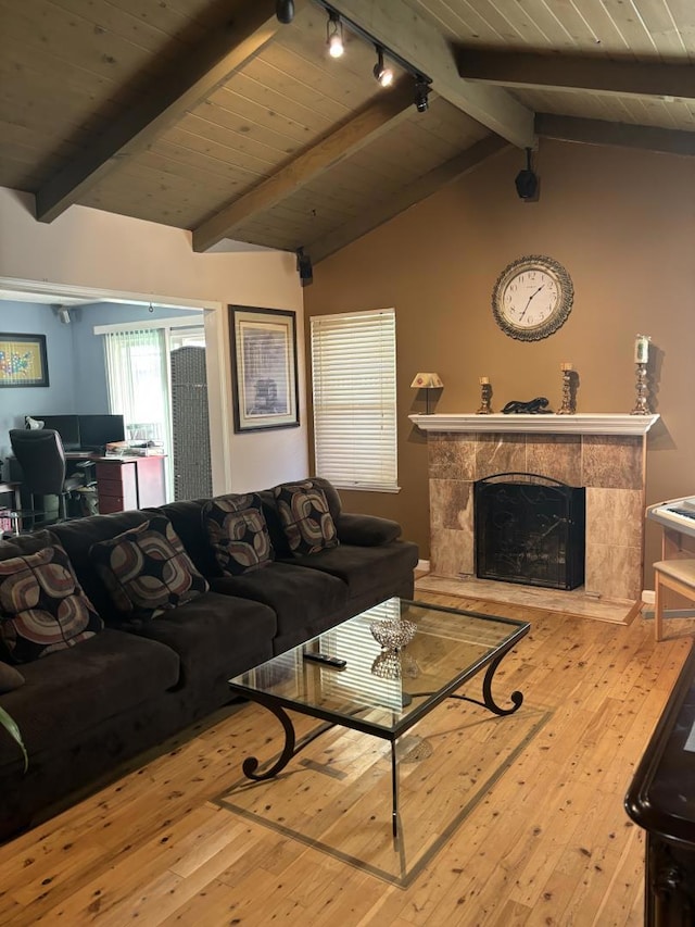 living room featuring rail lighting, lofted ceiling with beams, wooden ceiling, a fireplace, and hardwood / wood-style floors