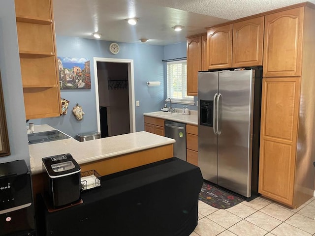 kitchen featuring sink, light tile patterned floors, stainless steel appliances, and a textured ceiling