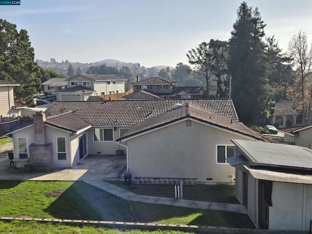 rear view of house with a mountain view, a yard, and a patio area