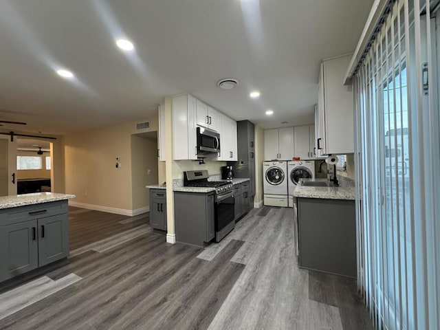 kitchen with gray cabinets, stainless steel appliances, white cabinetry, and washer and dryer