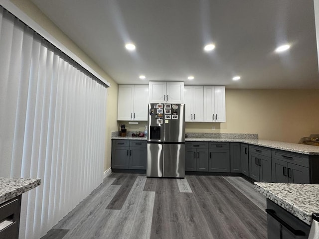 kitchen with light stone countertops, white cabinets, wood-type flooring, stainless steel fridge, and gray cabinets