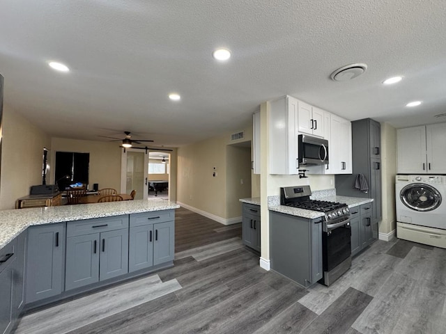 kitchen with ceiling fan, washer / dryer, stainless steel appliances, a textured ceiling, and white cabinets