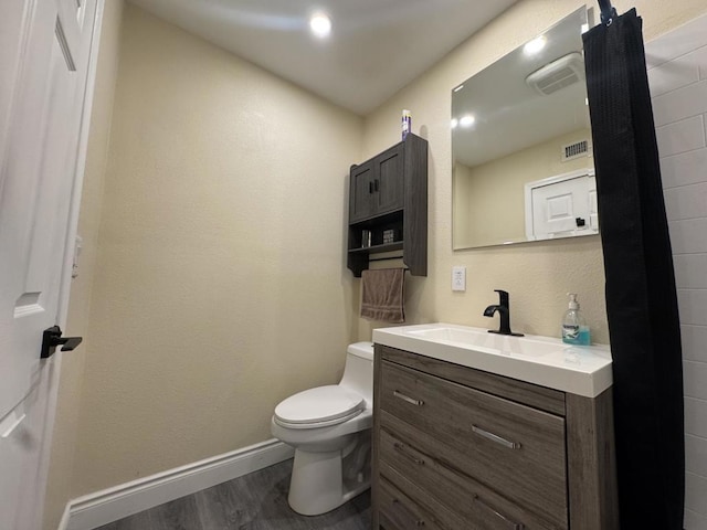 bathroom with toilet, vanity, and hardwood / wood-style floors