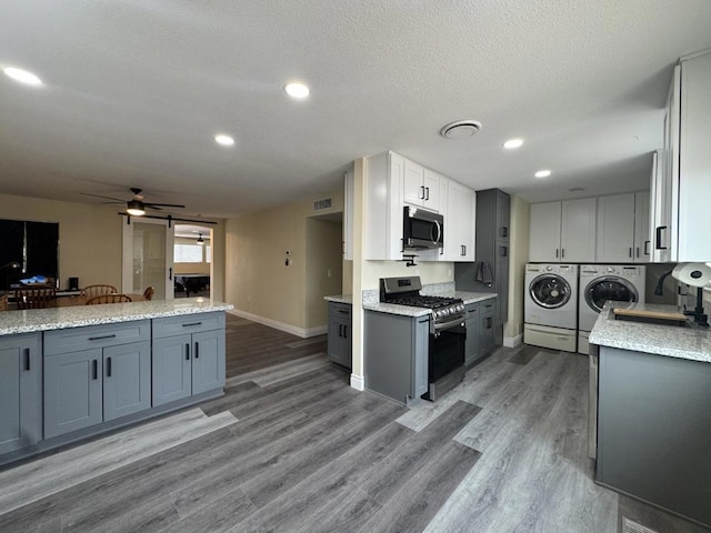 kitchen with ceiling fan, appliances with stainless steel finishes, washer and dryer, white cabinets, and sink