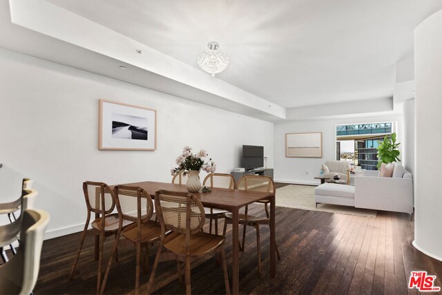 dining space with a raised ceiling and dark hardwood / wood-style floors