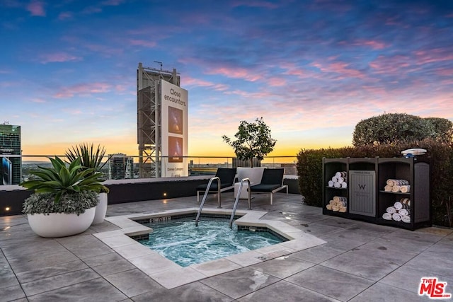 pool at dusk with a hot tub