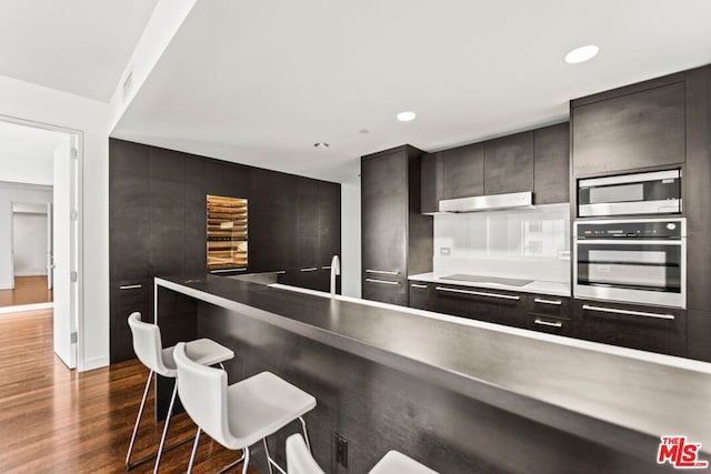 kitchen with a breakfast bar, stainless steel appliances, and dark wood-type flooring