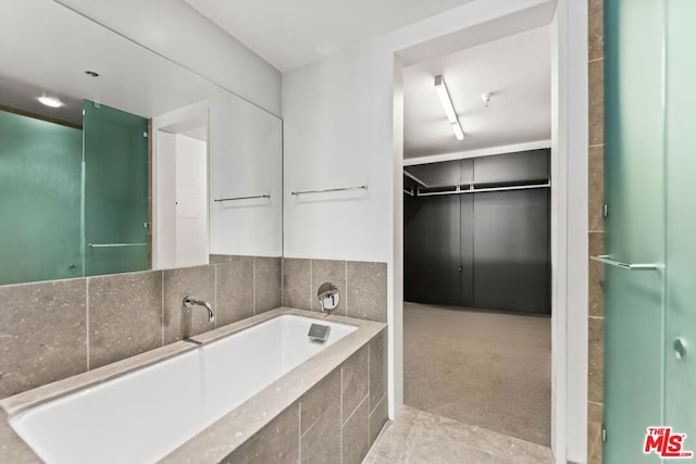 bathroom with tile patterned floors and tiled bath