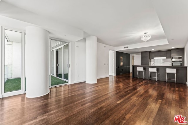 unfurnished living room with dark wood-type flooring and a chandelier