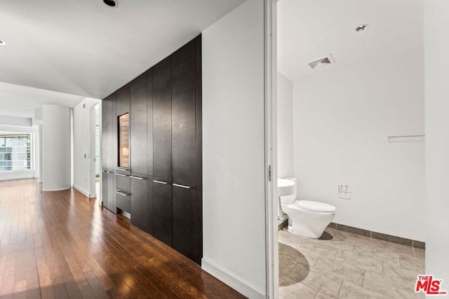 corridor with wood-type flooring and vaulted ceiling