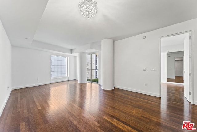 unfurnished living room featuring a chandelier and dark wood-type flooring