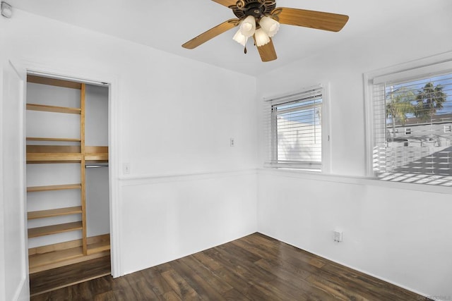 empty room featuring ceiling fan, dark wood-type flooring, and a healthy amount of sunlight