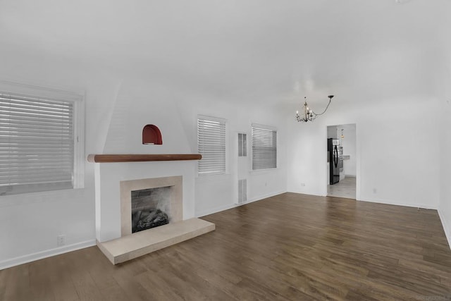 unfurnished living room with a fireplace, wood-type flooring, and an inviting chandelier