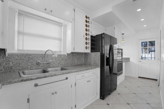 kitchen with backsplash, black fridge, white cabinetry, and pendant lighting