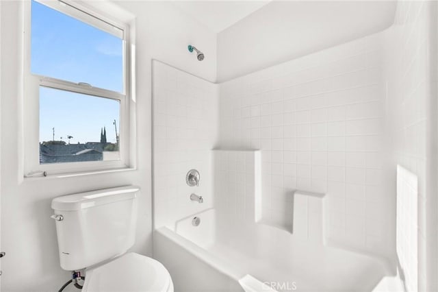 bathroom featuring tiled shower / bath combo and toilet