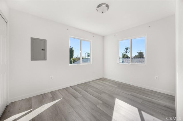 unfurnished room featuring electric panel and light hardwood / wood-style flooring